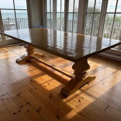 Sale Photo Thumbnail #12: Large trestle-style dining table with a planked wood top and glossy finish, set in a sunlit room.