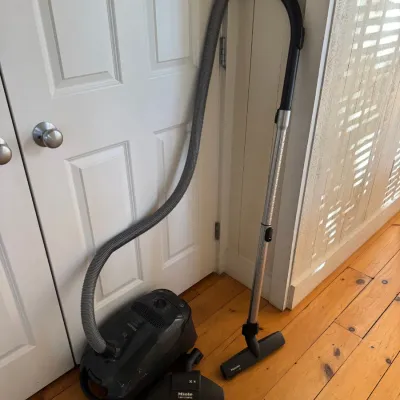Sale Photo Thumbnail #56: Dark gray Miele canister vacuum cleaner with hose, wand, floor nozzle, and TurboComfort attachment.