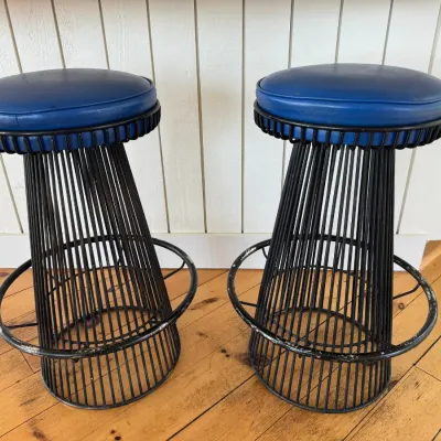 Sale Photo Thumbnail #15: Pair of mid-century modern wire frame barstools featuring blue vinyl seats and integrated footrests, showing light wear to the black finish.