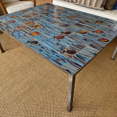 Sale Photo Thumbnail #11: Mid-century modern tiled coffee table featuring a blue glazed surface with colorful swimming fish motifs set on a metal frame.