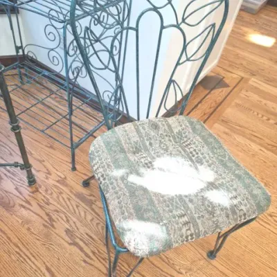 Sale Photo Thumbnail #92: Vintage metal wrought iron chair featuring a botanical heart-shaped backrest and a patterned upholstered seat cushion, displayed alongside matching wire shelving.