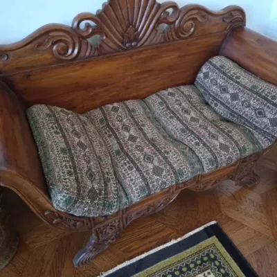 Sale Photo Thumbnail #13: Ornately carved wooden settee featuring a shell crest and scrollwork, fitted with patterned upholstered cushions.