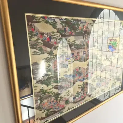 Sale Photo Thumbnail #64: Framed Japanese-style narrative artwork featuring detailed village scenes, housed in a metallic gold frame with black matting.