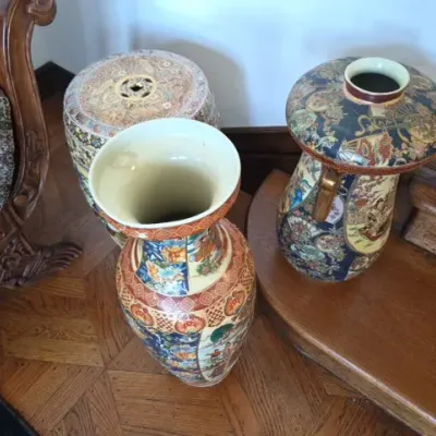 Sale Photo Thumbnail #121: Collection of three Asian Satsuma-style porcelain pieces, including two tall floor vases and a drum garden stool with intricate hand-painted floral and figurative scenes.