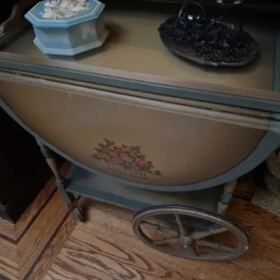 Sale Photo Thumbnail #108: Vintage painted drop-leaf tea cart featuring floral stenciling, large wooden spoke wheels, and a glass-top removable tray.