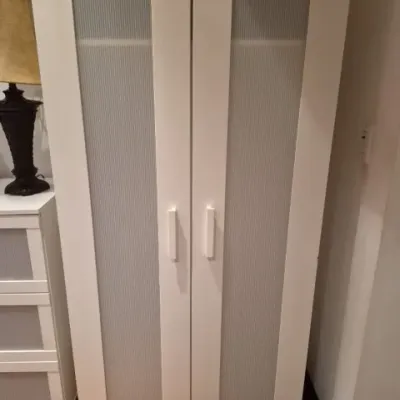 Sale Photo Thumbnail #102: Contemporary white tall storage cabinet with two doors featuring reeded glass insert panels.