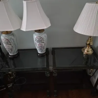 Sale Photo Thumbnail #101: Pair of dark wood end tables with glass tops, topped with two traditional floral ceramic ginger jar lamps and a brass table lamp with a pleated shade.