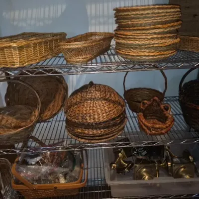 Sale Photo Thumbnail #151: Wire shelving rack holding a variety of woven baskets, paper plate holders, and a plastic bin of brass door hardware.