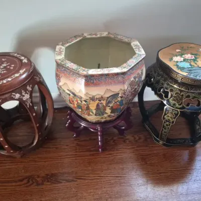 Sale Photo Thumbnail #122: Set of three Asian-style accent pieces, including a large octagonal Satsuma-style porcelain fishbowl planter on a wooden stand flanked by two decorative garden stools featuring mother-of-pearl inlay and painted floral designs.