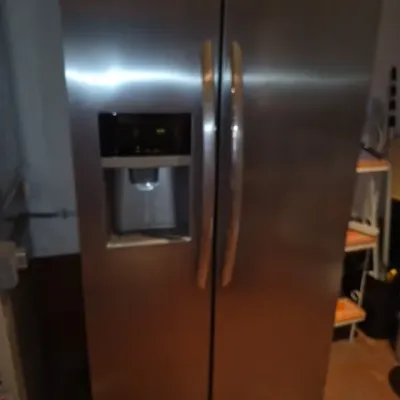 Sale Photo Thumbnail #144: Modern stainless steel side-by-side refrigerator featuring vertical bow handles and an exterior water and ice dispenser.