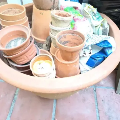Sale Photo Thumbnail #169: Large terracotta planter bowl filled with various smaller terracotta, plastic, and peat pots along with gardening supply bags.