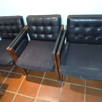 Sale Photo Thumbnail #100: Set of three mid-century modern waiting room armchairs featuring tufted black vinyl backrests, dark fabric seats, and wood frames.