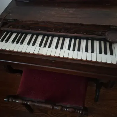 Sale Photo Thumbnail #48: Antique Mason & Hamlin dark wood pump organ or melodeon with a matching red upholstered bench. The instrument features intricate fretwork detailing above the keys and shows signs of age-appropriate wear.