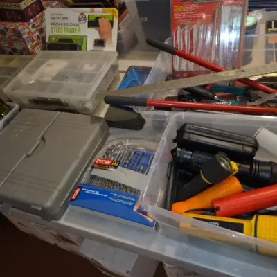 Sale Photo Thumbnail #164: Assorted workshop tools and hardware including flashlights, drill bits, hand tools, and a Franklin Sensors stud finder arranged in plastic storage bins.