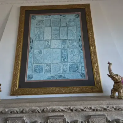 Sale Photo Thumbnail #59: Large ornate gilt framed artwork displayed above a mantel, flanked by a pair of decorative elephant figurines with raised trunks.