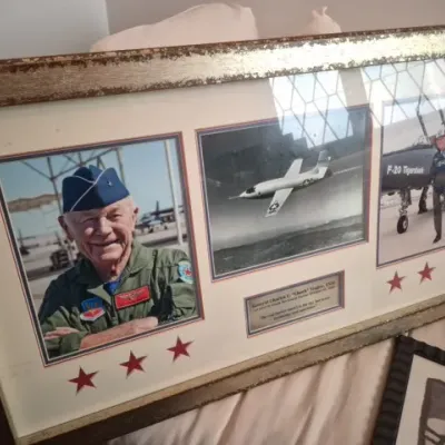 Sale Photo Thumbnail #72: Framed General Charles E. "Chuck" Yeager commemorative display featuring portrait and aircraft photos, housed in a distressed wooden frame.