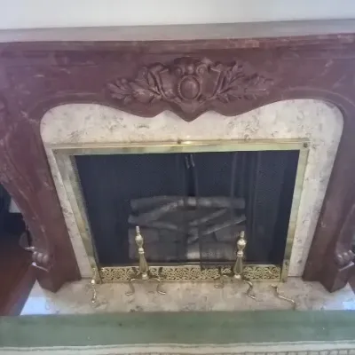 Sale Photo Thumbnail #47: Ornate French Rococo-style carved reddish-brown marble fireplace mantle with marble surround, brass-framed mesh screen, and brass andirons.