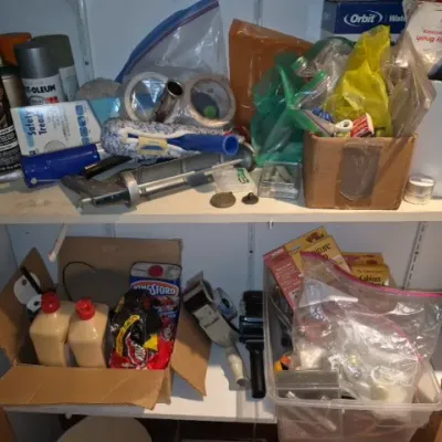Sale Photo Thumbnail #168: Storage shelves filled with assorted household items, including spray paint cans, caulk guns, tape, and plastic organizer bins.