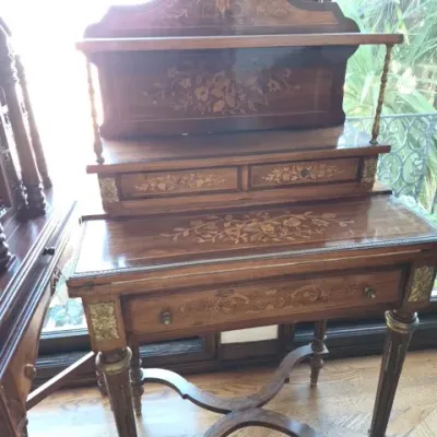 Sale Photo Thumbnail #17: Antique French-style marquetry desk featuring floral wood inlay, brass mounts, a top shelf display gallery, and small drawers over turned legs with an X-stretcher.