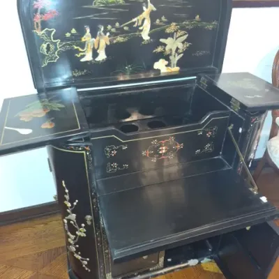 Sale Photo Thumbnail #12: Vintage Asian black lacquer bar cabinet with inlaid mother-of-pearl figures and hand-painted floral motifs, featuring fold-out sides and a drop-front surface.
