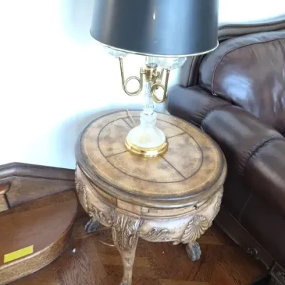 Sale Photo Thumbnail #94: Ornate traditional end table featuring carved claw-and-ball feet paired with a brass and glass table lamp topped with a black lampshade.