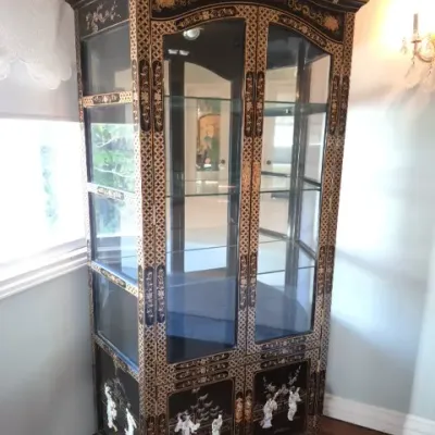 Sale Photo Thumbnail #30: Asian-style black lacquer display cabinet featuring ornate gold geometric accents and inlaid mother-of-pearl figures on the lower door panels.