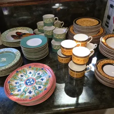 Sale Photo Thumbnail #131: Large collection of ceramic dinnerware including green scroll-patterned plates and teacups alongside gold and black patterned china sets.