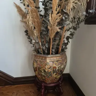 Sale Photo Thumbnail #105: Large Asian-style hand-painted ceramic fishbowl planter with gold accents, set on a dark wood stand and filled with dried botanical stems.