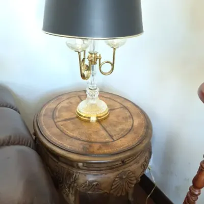 Sale Photo Thumbnail #93: Traditional carved wood round side table with a leather-insert top, featuring a brass and cut crystal lamp topped with a black drum shade.
