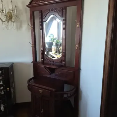 Sale Photo Thumbnail #29: Victorian-style wooden hall tree featuring a central shaped mirror, brass coat hooks, carved broken-arch pediment, and a lower storage cabinet with side umbrella stands.