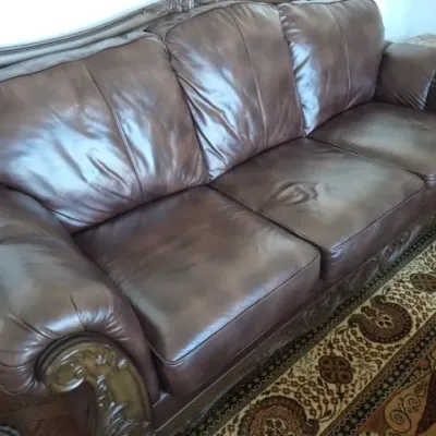 Sale Photo Thumbnail #26: Traditional dark brown leather sofa featuring carved wood trim and rolled armrests.