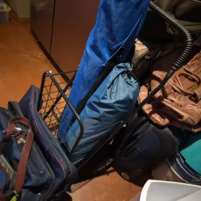 Sale Photo Thumbnail #183: Collection of assorted luggage, duffel bags, and a wire rolling utility cart, including a brown leather backpack and various nylon travel bags.