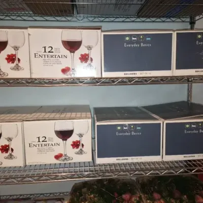 Sale Photo Thumbnail #154: Wire rack filled with boxed glassware, including 12-piece Entertain red wine glass sets and Everyday Basics balloon glass sets.