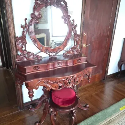 Sale Photo Thumbnail #32: Ornately carved Victorian style vanity table with attached oval mirror and matching red velvet upholstered stool.
