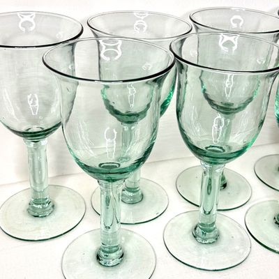 Set of hand-blown light green glass goblets with flared rims and thick stems.