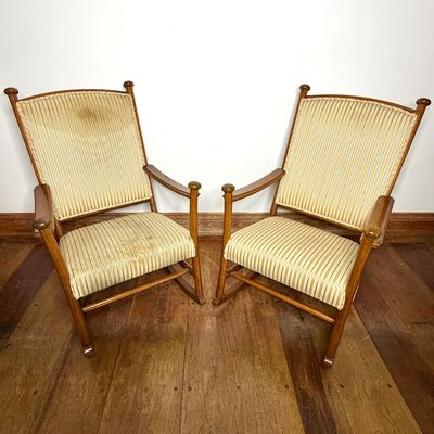 Pair of antique wooden rocking chairs featuring striped fabric upholstery and turned finial accents.
