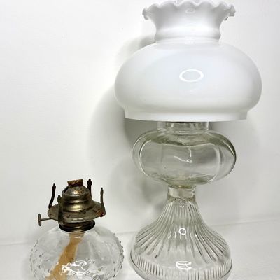Vintage glass oil lamps, including a large clear ribbed base lamp with a white glass shade and chimney, alongside a smaller hobnail...