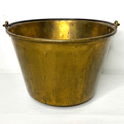 Antique solid brass bucket with a iron bail handle, showing an aged patina and minor surface wear.