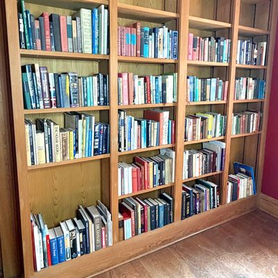 Large multi-section oak built-in bookcase filled with a wide collection of vintage hardcover books.