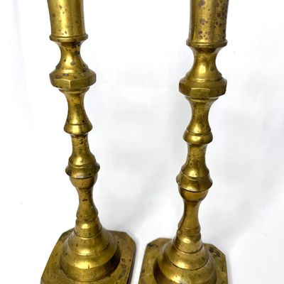 Pair of vintage brass candlestick holders featuring baluster stems and square bases, showing aged patina.
