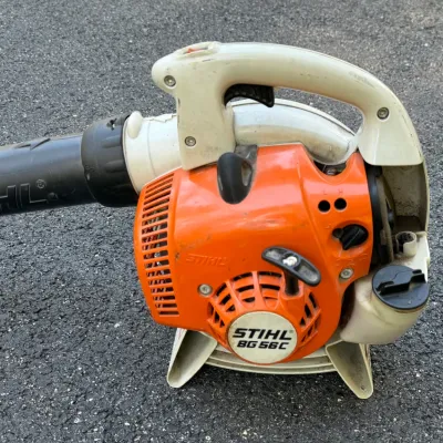 Stihl BG 56 C handheld gas-powered leaf blower resting on asphalt.