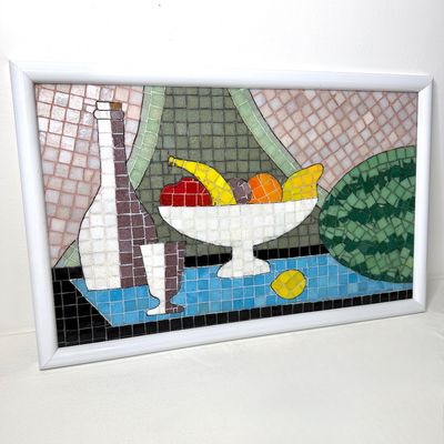 Mid-century tile mosaic still life artwork featuring a bottle, fruit bowl, and watermelon, framed in a simple white frame.