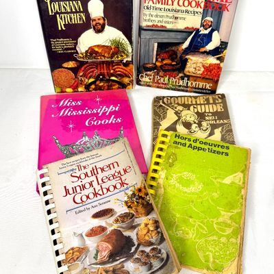 Collection of vintage Southern and Cajun cookbooks, including titles by Chef Paul Prudhomme, in worn condition.