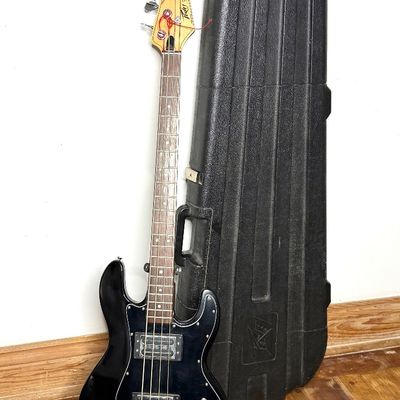 Vintage Peavey T-40 electric bass guitar in black finish, paired with its original Peavey molded hard shell case.