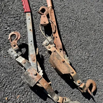 Pair of heavy-duty hand-lever cable pullers, commonly called come-alongs, showing surface rust and wear from use.