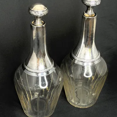 Pair of antique cut glass decanters featuring silver-plated necks and matching stoppers.