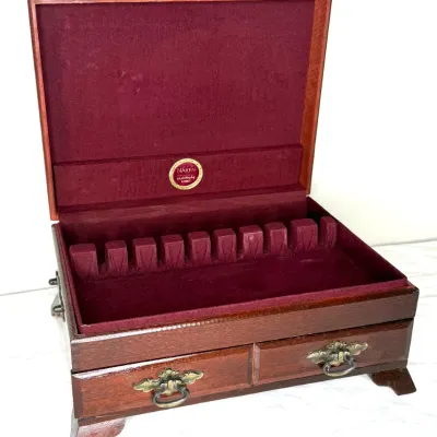 Vintage Naken wooden silverware chest featuring a burgundy felt-lined interior, lower storage drawer, and decorative brass hardware.