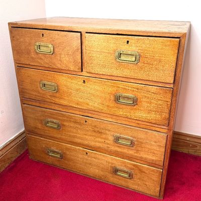 Vintage campaign-style wooden chest of drawers featuring recessed brass flush-mount handles and keyholes.