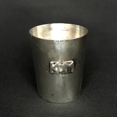 Small sterling silver shot glass or jigger featuring an applied monogram badge on the front.