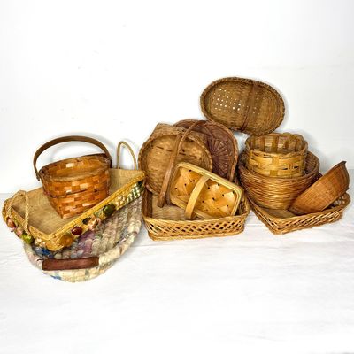 Collection of vintage woven baskets in various shapes, sizes, and styles, including hand-handled gather baskets and trays.